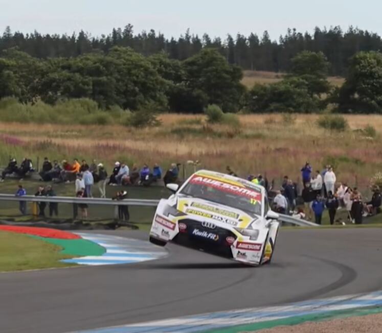 The Awesome-sponsored #17 Steel Seal Power Maxed Racing Audi S3 airborne over the kerbs at Knockhill in front of spectators on the grass banking