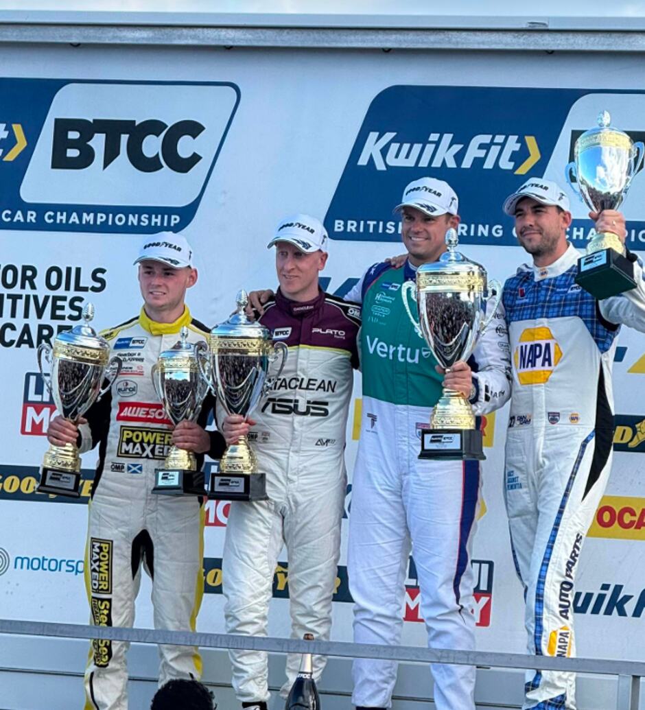 Dexter Patterson in his Awesome Power Maxed Racing race suit holding a trophy alongside three other drivers at the Knockhill awards presentation