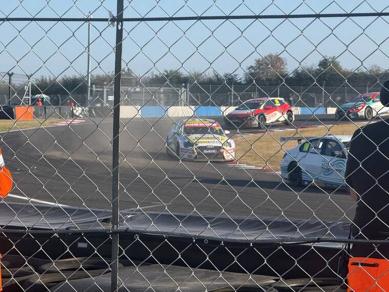 Cars running wide with dust in the air at Donington Park, the Awesome-sponsored #17 Audi S3 among them, seen from the spectator side of the fence